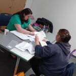 Two women looking at paperwork across a desk